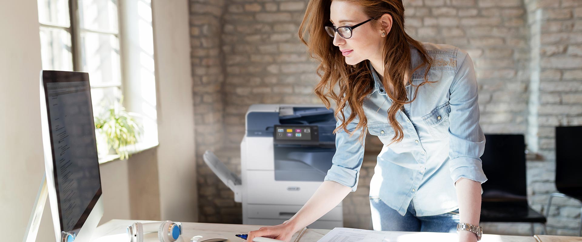 A young woman sending a print job from her computer to the office printer.